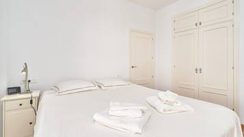 Un dormitorio con cama, mesita de noche, lámpara y armario.