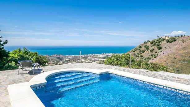 Una piscina con vista sul mare e su una collina.