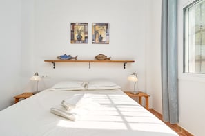 Un lit bien fait, avec des oreillers, une table de chevet en bois avec une lampe, une étagère avec des objets décoratifs et une fenêtre avec des rideaux.