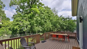 Eine Holzterrasse mit Tisch und Stühlen, umgeben von Bäumen.