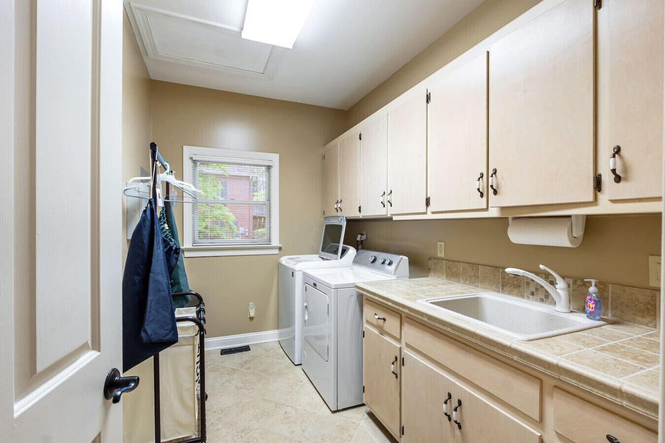 A laundry room with a washing machine, dryer, and a sink with a soap dispenser.