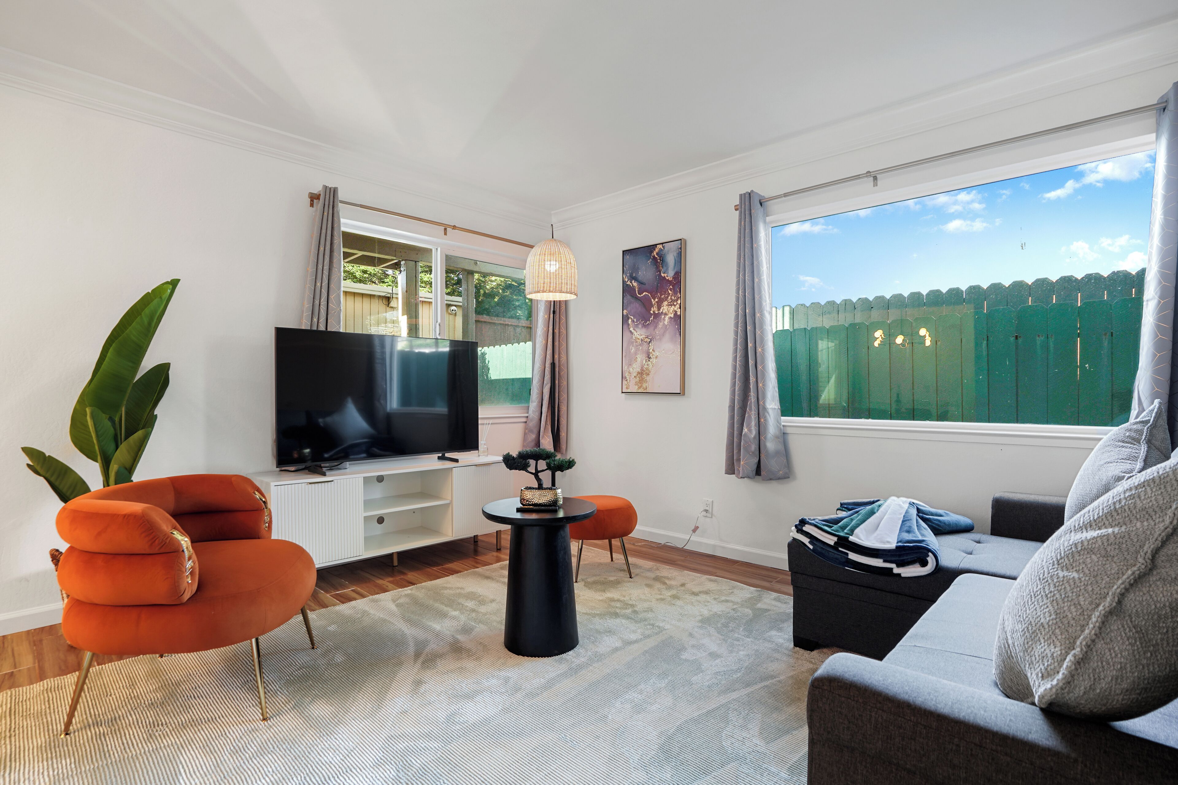 A modern living room with a flat-screen TV, a round black coffee table, and a grey sofa.