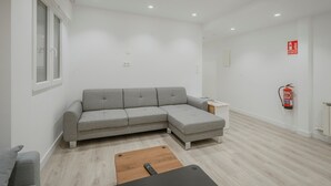 Un salon moderne avec un canapé d’angle gris, une table basse en bois et une petite table d’appoint.