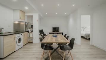 Eine moderne Küche mit Einbauwaschmaschine, einem Esstisch mit Stühlen und einem Fernseher im Hintergrund.