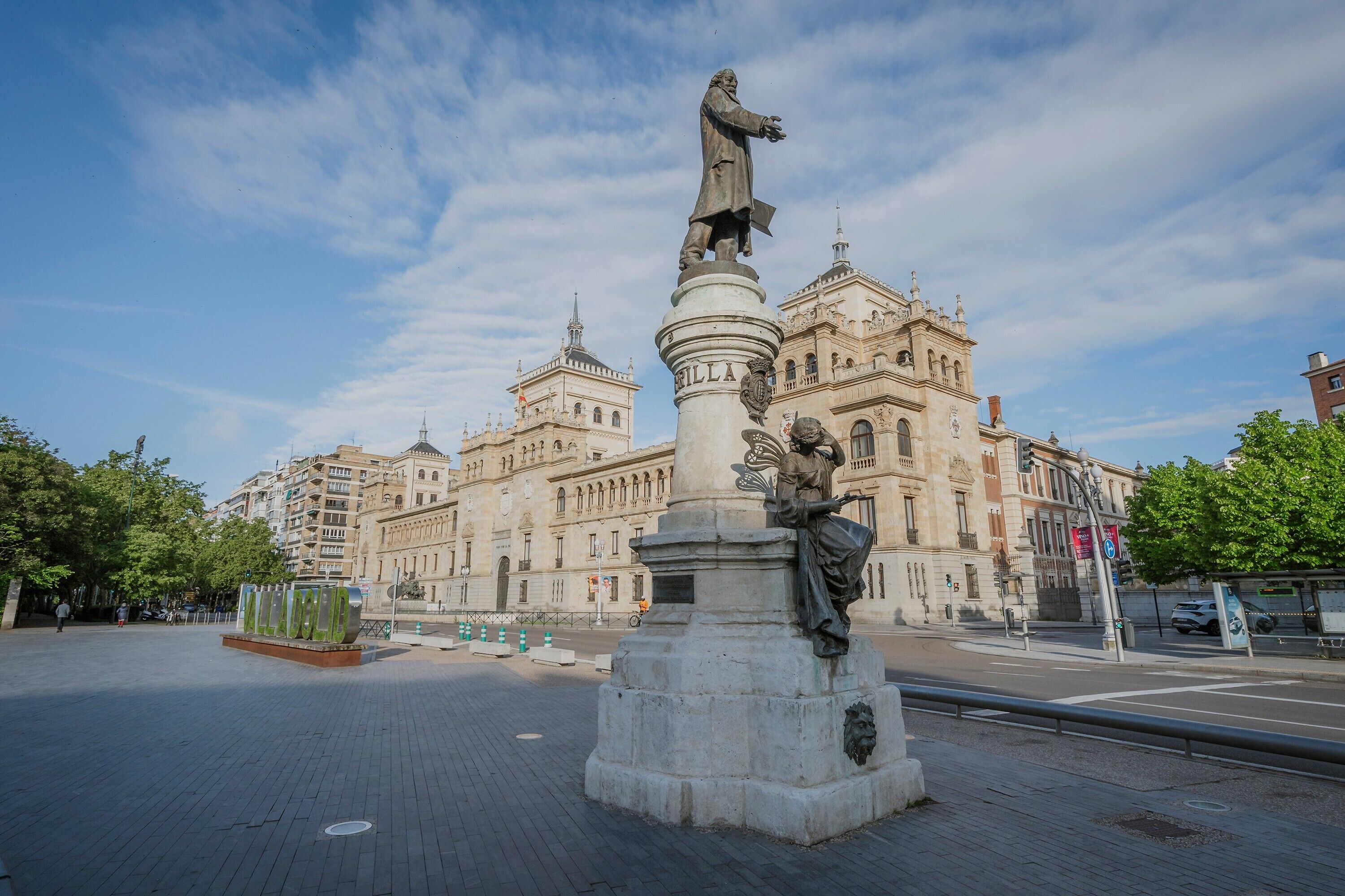Una estatua en una plaza con un edificio grande al fondo.