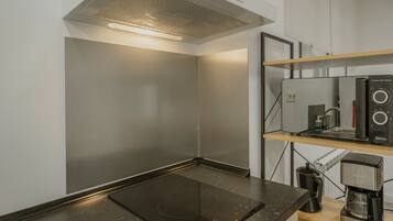 Una cocina moderna con una placa de inducción integrada, una cafetera y un espejo con forma de ola tridimensional.