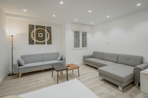 Ein modernes Wohnzimmer mit zwei grauen Sofas, einem kleinen Holztisch und einer Stehlampe.