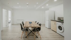 Une cuisine moderne équipée d’une table à manger, de chaises, d’un lave-linge et d’un réfrigérateur.