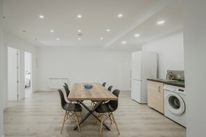 A modern kitchen with a dining table, chairs, a washing machine, and a refrigerator. - Apartment 'Mónaco' with Wi-Fi (Valladolid)