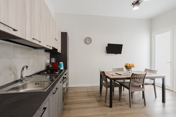 A modern kitchen with a sink, stove, and dining area with chairs and a table.