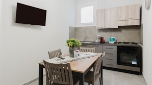 A compact kitchen with a dining table, chairs, a TV, and a built-in oven.