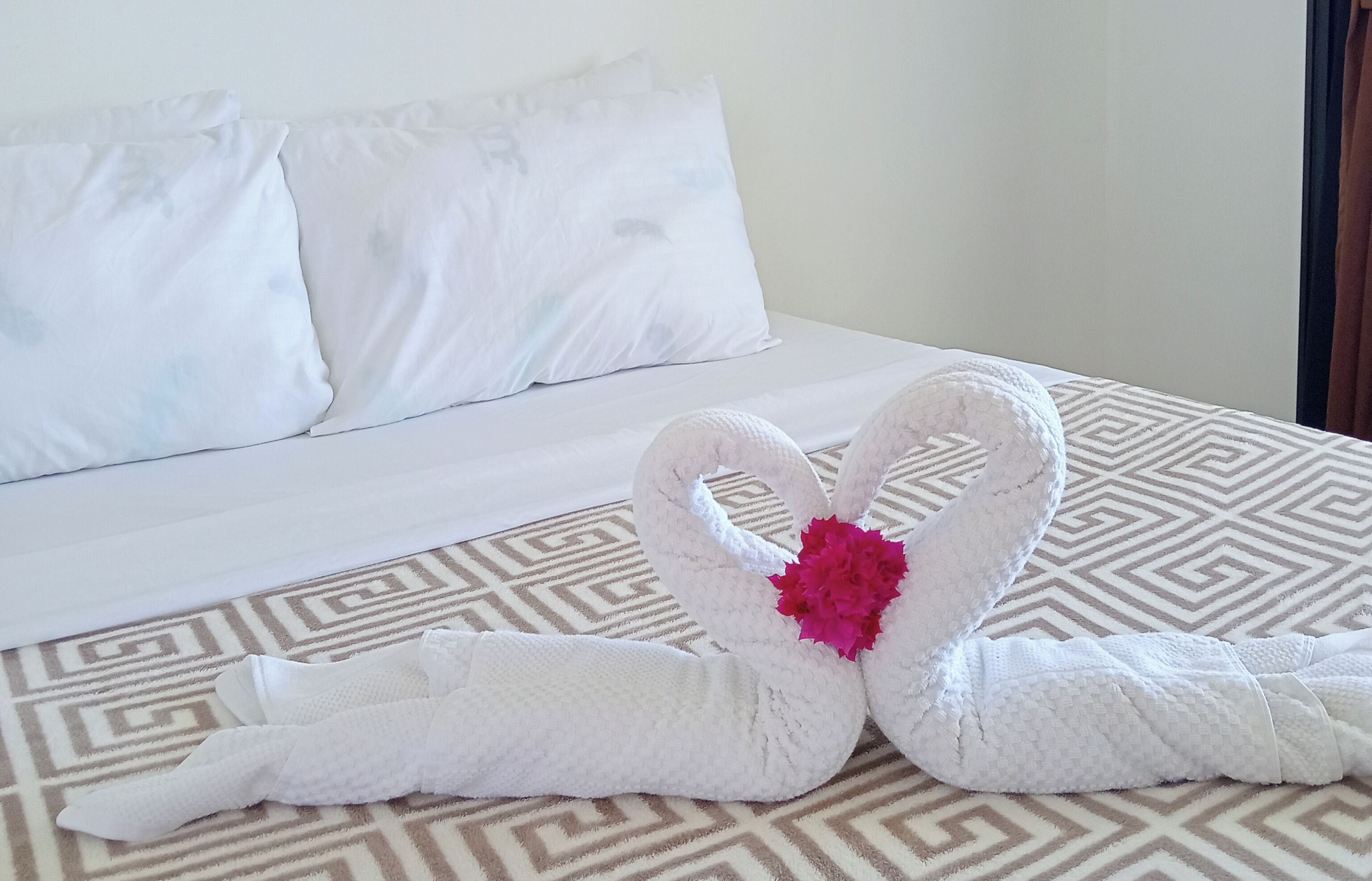 Ein Hotelzimmer mit einem Bett, Kissen und einem geometrisch gemusterten Teppich.