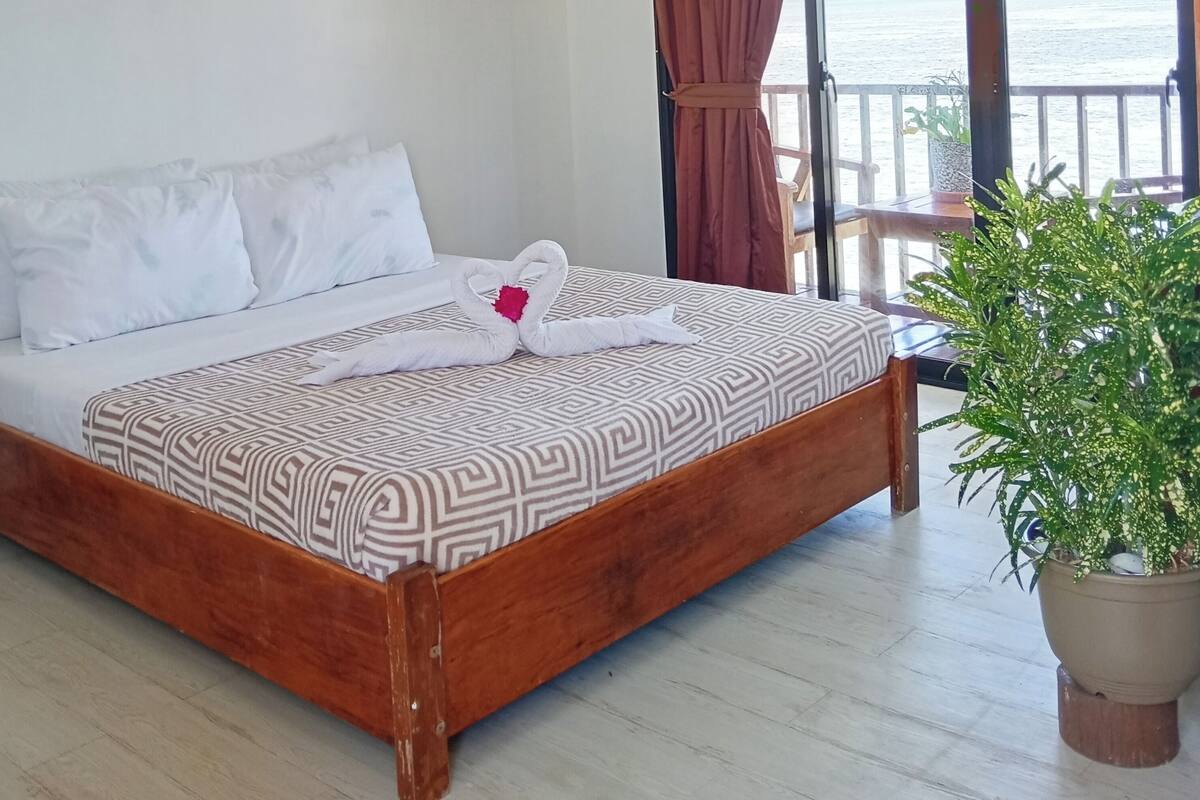A bed with a patterned bedspread and a heart-shaped towel arrangement.