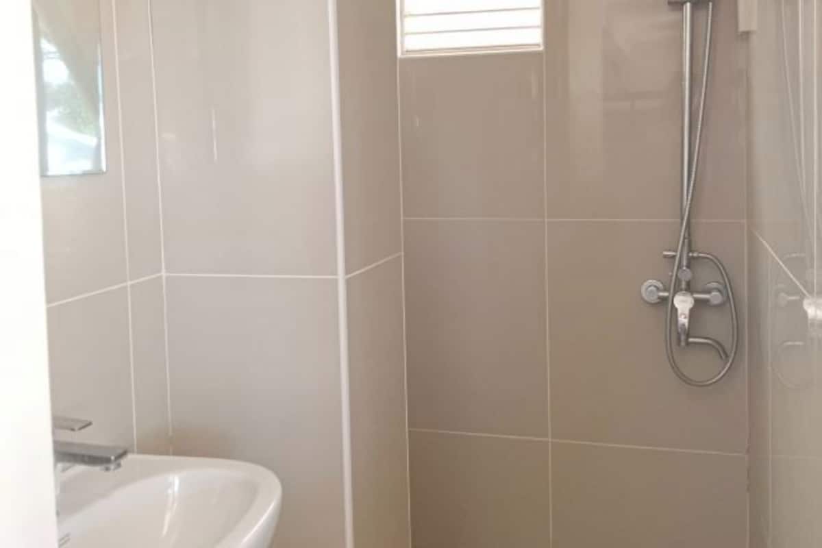 A bathroom with a shower, a sink, and tiled walls.