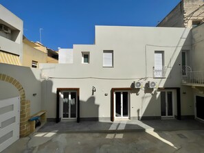 A courtyard with a white building, two doors, and a small window. - Apartment 'Lazzara 19 - Home 01' with Balcony, Wi-Fi and Air Conditioning (Marsala)