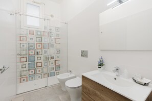 A bathroom with a shower, toilet, sink, and mirror. - Apartment 'Lazzara 19 - Home 01' with Balcony, Wi-Fi and Air Conditioning (Marsala)