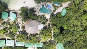 Vista aérea de un complejo turístico con múltiples piscinas, un edificio central amplio y varias sombrillas de playa.