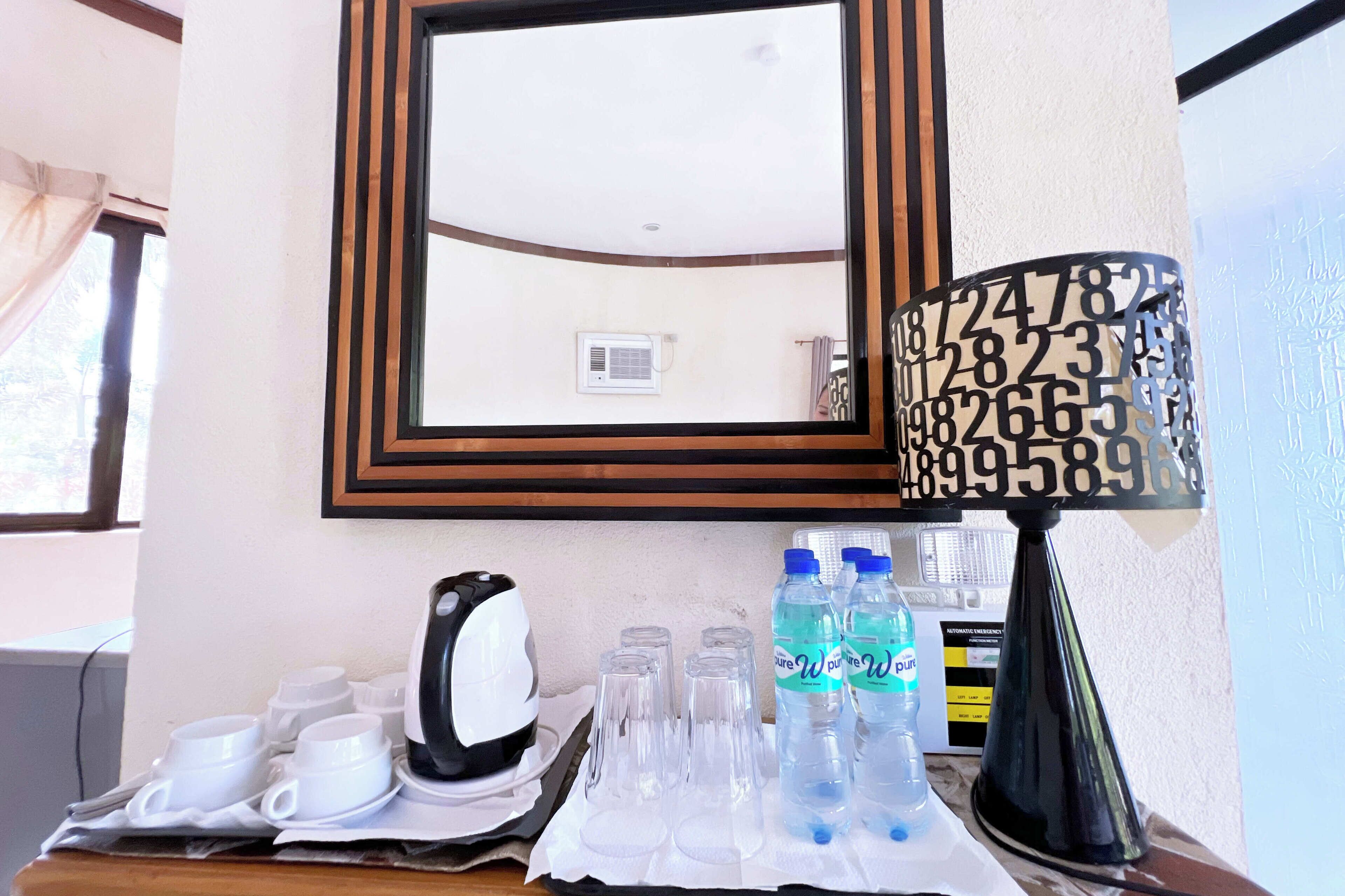 Une chambre d’hôtel équipée d’une machine à café, de tasses, de verres et de bouteilles d’eau sur le comptoir.