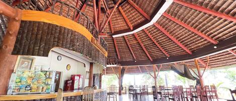 An indoor dining area with a high ceiling, wooden beams, and a counter with snacks.