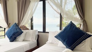 Habitación de hotel con dos camas, cada una con ropa de cama blanca y almohadas azules.