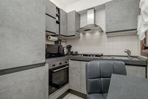 Een moderne keuken met grijze kastjes, een inbouwoven, een gasfornuis en een spoelbak.