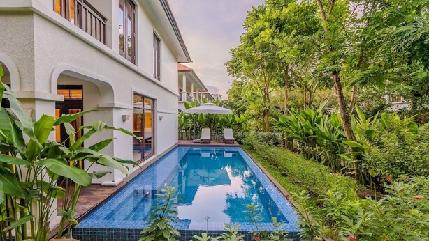 Une maison moderne dotée d’une piscine, le tout entouré d’une végétation luxuriante.