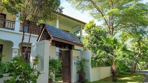 Un bâtiment à deux étages doté d’une entrée couverte, entouré d’une végétation luxuriante et d’une pelouse bien entretenue.