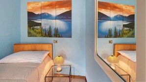 Een slaapkamer met een bed, bedlampje en een groot landschap op de muur.
