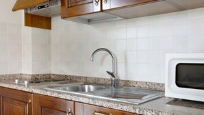 A kitchen with wooden cabinets, a stainless steel sink, and a white microwave. - Studio Apartment 'Numero 3' with Shared Garden and Air Conditioning (Montopoli in Val d'Arno)
