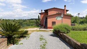A single-story building with a red facade, a gravel driveway, and a stone wall. - Studio Apartment 'Numero 3' with Shared Garden and Air Conditioning (Montopoli in Val d'Arno)