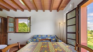 A room with a bed, a table, and a window with a view of greenery. - Studio Apartment 'Numero 3' with Shared Garden and Air Conditioning (Montopoli in Val d'Arno)