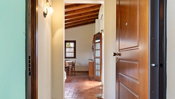 Un pasillo que conduce a un comedor con techo de madera y piso de baldosas.