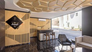 Un vestíbulo moderno con mostrador de recepción, zona de bar y asientos.