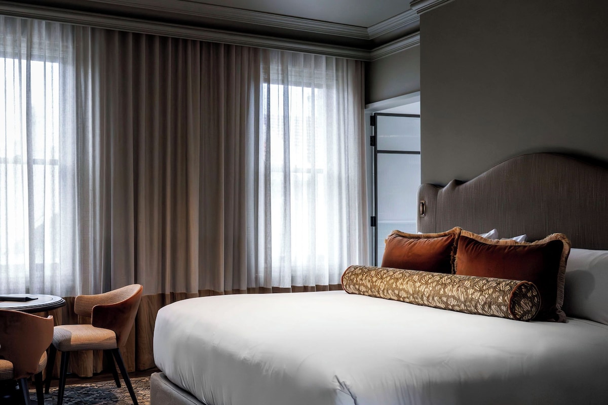 A hotel room with a large bed, a desk, and a chair.