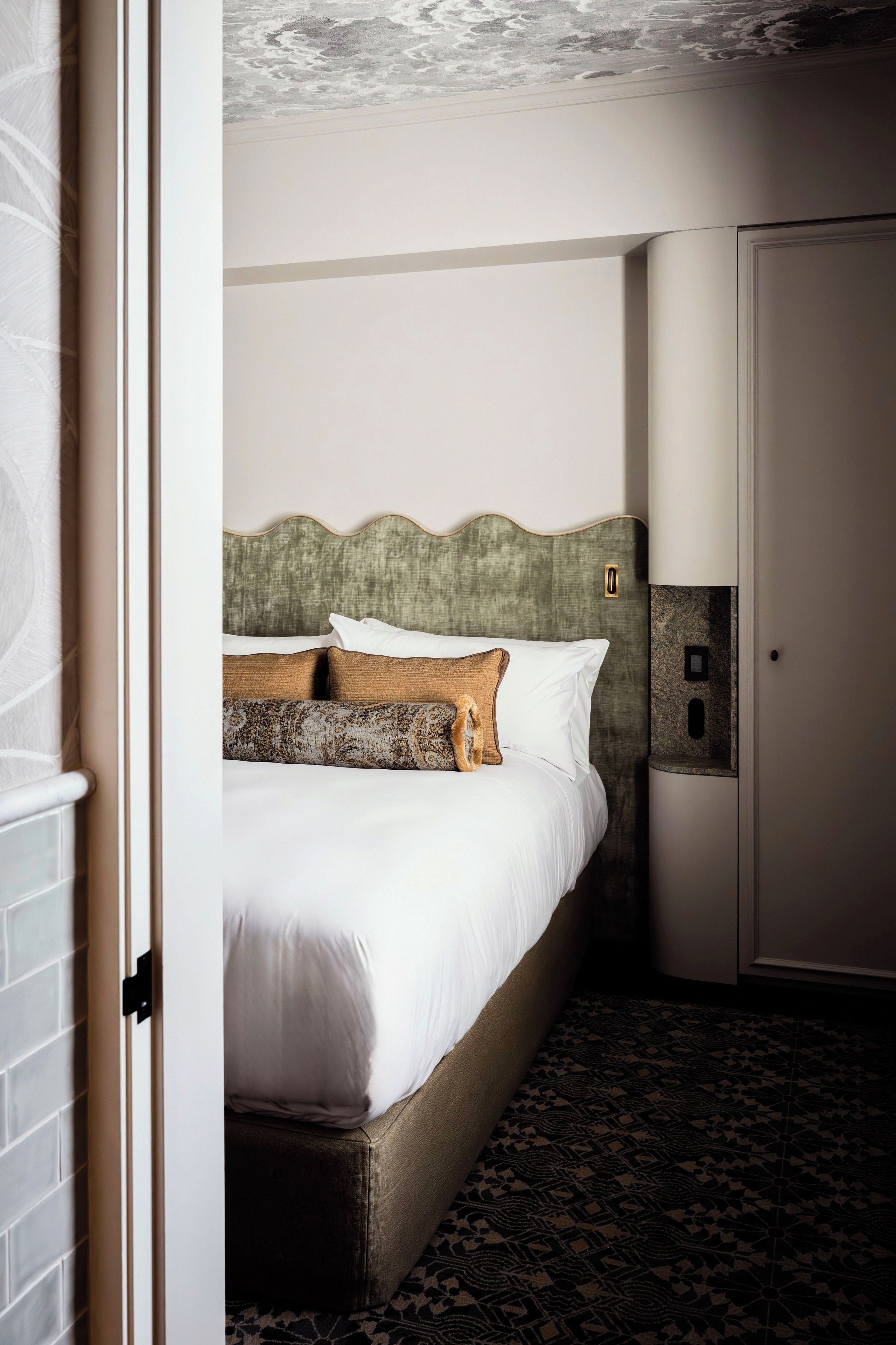 Habitación de hotel con cama, puerta y alfombra estampada.