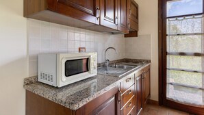 Une cuisine avec des meubles en bois, un four à micro-ondes, un évier et une fenêtre.