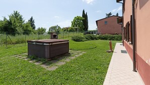 Un jardin avec un abri en bois, un sentier et un bâtiment à la façade rouge.