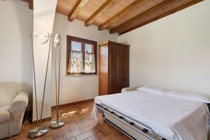 A bedroom with a bed, a wardrobe, a floor lamp, and a window.