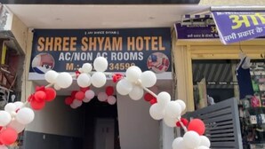 Das Außere des Shree Shyam Hotels mit einem Schild, das klimatisierte und nicht-klimatisierte Zimmer bewirbt.