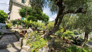 A stone pathway leading to a house with a garden, surrounded by trees and potted plants. - Apartment 'Giannina' with Sea View, Wi-Fi and Air Conditioning (Bonassola)