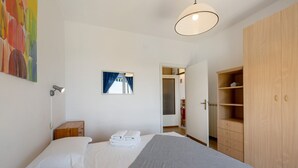 A bedroom with a bed, a bedside table with towels, a wardrobe, a painting, and a window with curtains. - Apartment 'Giannina' with Sea View, Wi-Fi and Air Conditioning (Bonassola)