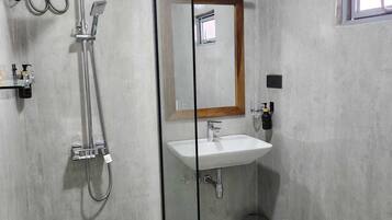 Une salle de bain avec une douche à parois de verre, un lavabo blanc et un miroir avec un cadre en bois.