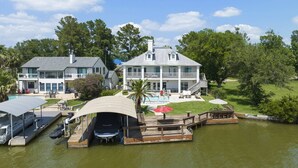Une grande maison avec une piscine, un quai et un bateau.