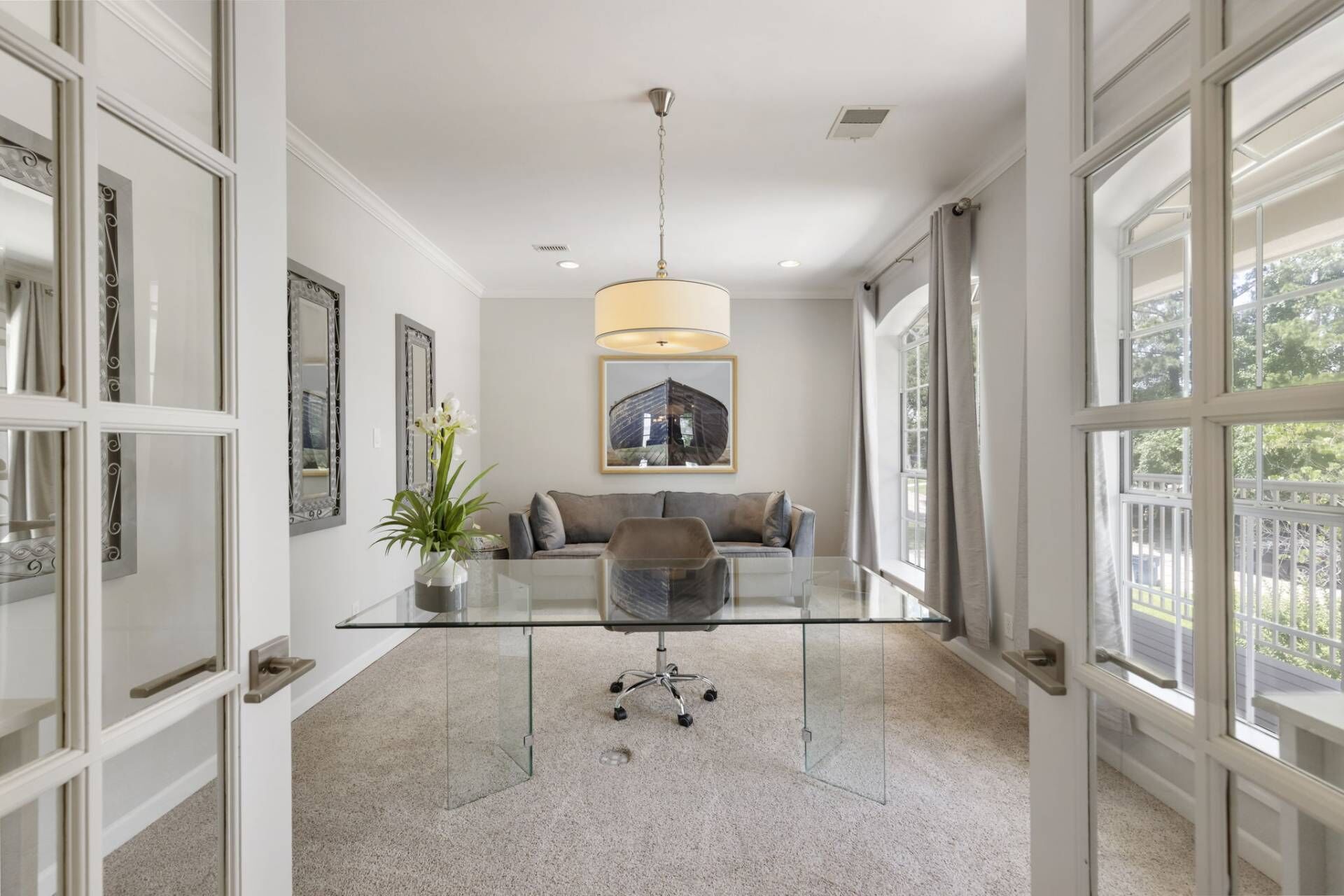 Un salon moderne avec une table basse en verre, un canapé gris et un luminaire suspendu.