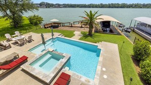Une piscine avec un jacuzzi, des chaises longues et une terrasse offrant une vue sur un lac.