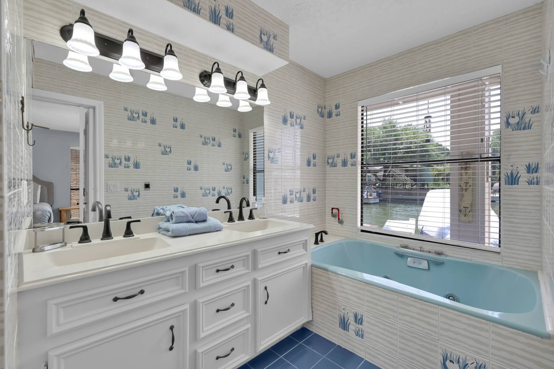 A bathroom with a double sink vanity, a bathtub, and a window with blinds.