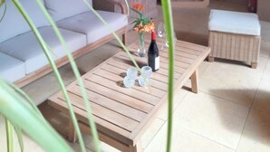 A cozy living area with a sofa, a wooden coffee table, and a small table with a bottle and glasses. There is a grill and a painting on the wall. - Clos saint Joseph (Orange)
