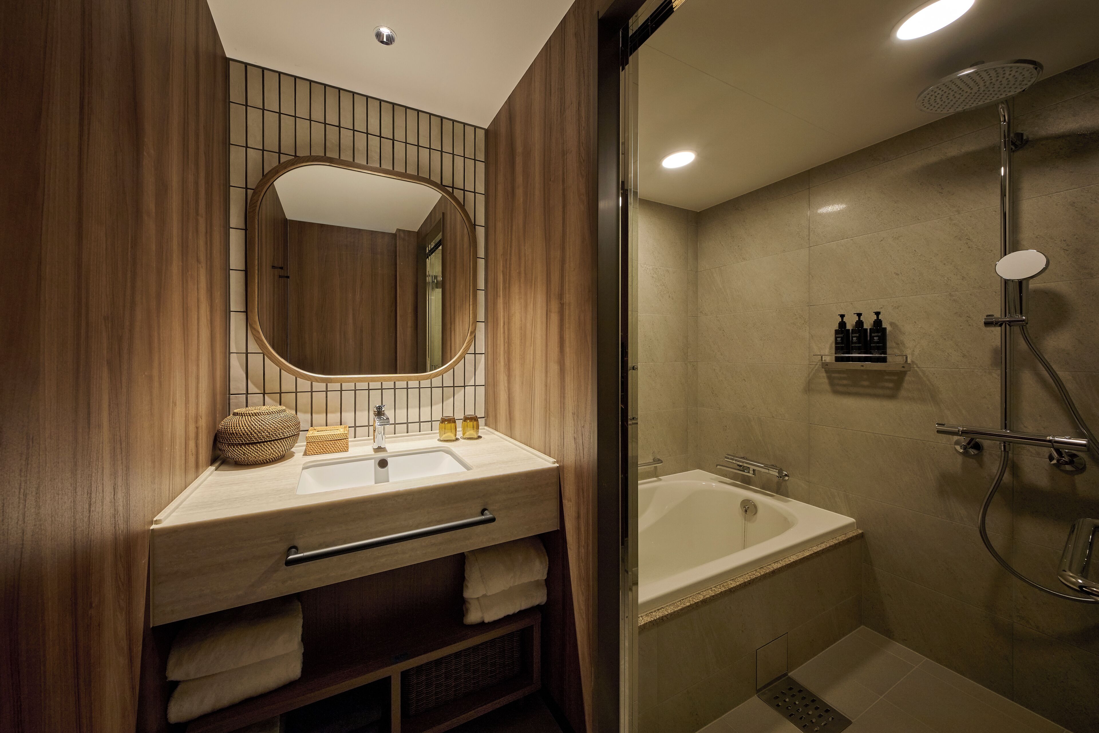 A modern bathroom with a wooden vanity, a large mirror, a bathtub, and a shower area.