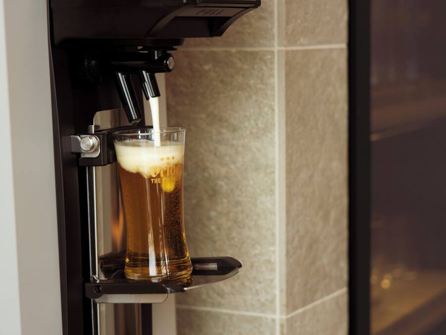 A glass of beer being dispensed from a machine.