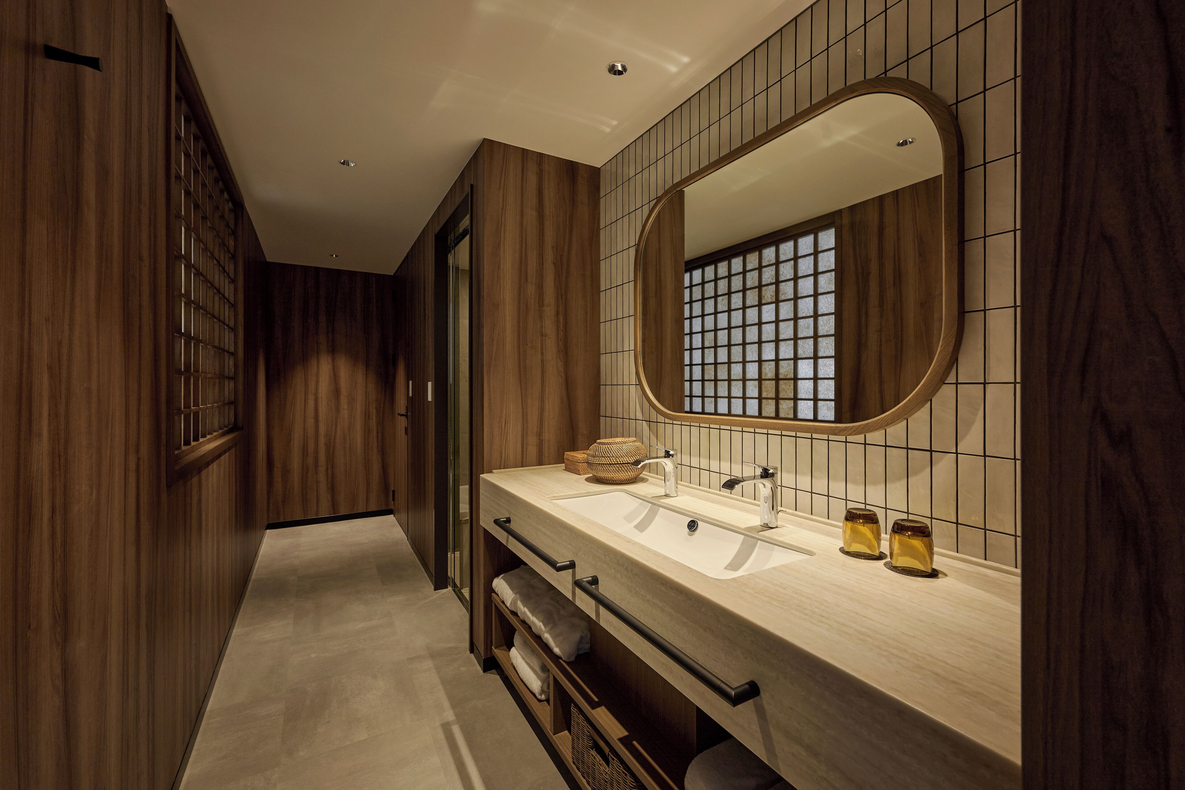 A modern bathroom with wooden paneling, a large mirror, and a dual sink vanity.